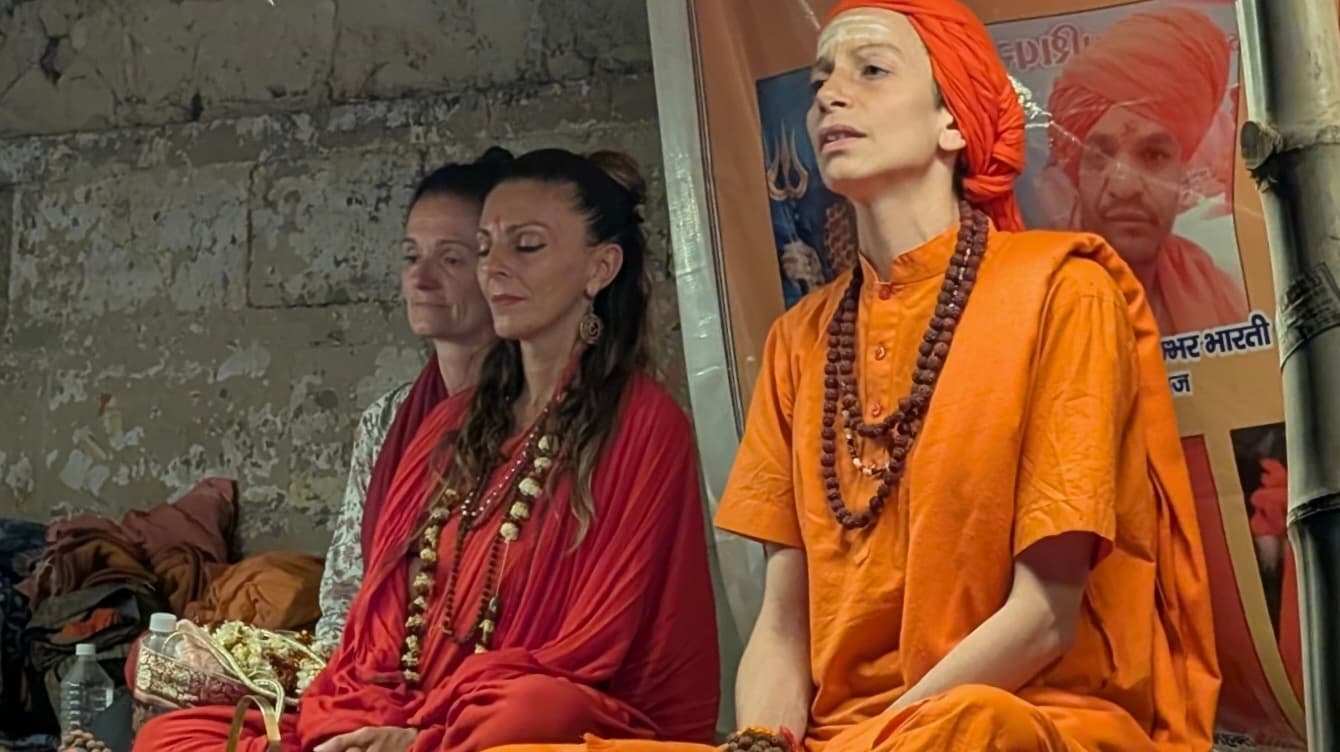 Devotees in saffron robes sitting and meditating quietly at the ghats in Banaras
