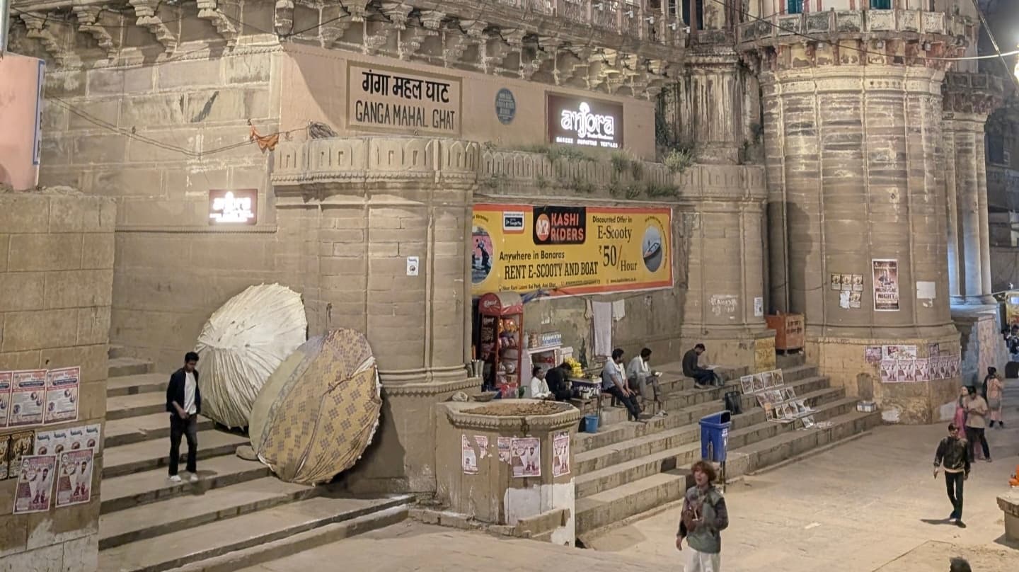 Ganga Mahal Ghat at night showing old stone architecture and small shops along the steps of Varanasi